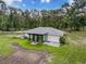 Aerial view showcasing the rear exterior and the manicured lawn under a partly cloudy sky at 10097 Weatherly Rd, Brooksville, FL 34601