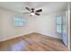 Bright bedroom featuring hardwood floors, ceiling fan, and a window to the porch at 10097 Weatherly Rd, Brooksville, FL 34601