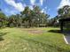 Lawn view of home and carport, accentuated by lush trees under a bright, partly cloudy sky at 10097 Weatherly Rd, Brooksville, FL 34601