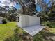 View of detached white garage with small window, accentuated by lush grass under a partly cloudy sky at 10097 Weatherly Rd, Brooksville, FL 34601