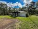 Rear exterior view with black framed windows and a manicured lawn under a partly cloudy sky at 10097 Weatherly Rd, Brooksville, FL 34601