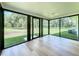 Bright sunroom featuring hardwood floors and multiple black frame windows offering backyard views at 10097 Weatherly Rd, Brooksville, FL 34601