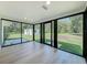 Bright sunroom featuring hardwood floors and multiple black frame windows offering backyard views at 10097 Weatherly Rd, Brooksville, FL 34601