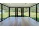 Bright sunroom featuring hardwood floors and multiple black frame windows offering backyard views at 10097 Weatherly Rd, Brooksville, FL 34601