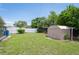 Large back yard featuring a shed, lush lawn, and white vinyl privacy fence at 10600 Oleander Dr, Port Richey, FL 34668