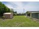 Expansive backyard featuring mature trees, a storage shed, and lush green space at 10600 Oleander Dr, Port Richey, FL 34668