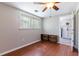 Cozy bedroom with a ceiling fan, wood-look flooring, and view into laundry area at 10600 Oleander Dr, Port Richey, FL 34668