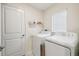 Well-lit laundry room with modern appliances, shelves, and a white door at 11395 Lavender Loop, Spring Hill, FL 34609