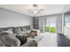 Bright living room featuring a comfortable sectional sofa, ceiling fan, and sliding glass doors to the backyard at 11395 Lavender Loop, Spring Hill, FL 34609