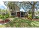 Exterior view of home with a well-manicured lawn and screened-in patio with ceiling fan at 11418 Tee Time Cir, New Port Richey, FL 34654