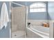 Bright bathroom featuring a glass-enclosed shower, soaking tub, and natural light from an arched window at 11418 Tee Time Cir, New Port Richey, FL 34654