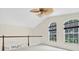 Open loft area with a ceiling fan, railing, and natural light streaming through the large windows at 11418 Tee Time Cir, New Port Richey, FL 34654
