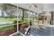Covered screened-in patio featuring fan, outdoor seating and a view of the lush landscaped backyard and waterway at 11418 Tee Time Cir, New Port Richey, FL 34654