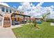 Spacious backyard features a manicured lawn, a charming pergola-covered bar, and stairs leading to a second-story deck at 13027 Beacon Ct, Hudson, FL 34667