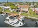Waterfront home featuring a boat dock, outdoor seating area, covered parking, and well-maintained lawn at 13027 Beacon Ct, Hudson, FL 34667