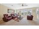 Bright living room featuring a leather sofa set, ceiling fan, and large windows at 13027 Beacon Ct, Hudson, FL 34667