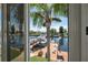 Waterfront view of a dock with boats and lush landscaping seen through sliding glass doors at 13027 Beacon Ct, Hudson, FL 34667