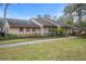 Single-story home with a well-maintained lawn, mature landscaping, and a covered front porch at 13134 Cypress Hill Dr, Hudson, FL 34669