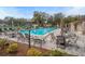 Community pool with tables and lounge chairs on a brick patio surrounded by trees and landscaping at 13134 Cypress Hill Dr, Hudson, FL 34669