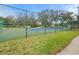 Exterior shot of a tennis court surrounded by a chain-link fence in active 55+ community at 13134 Cypress Hill Dr, Hudson, FL 34669