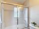 Bathroom with tiled walls and bathtub with sliding glass shower doors and small window at 13321 Norman Cir, Hudson, FL 34669