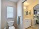 Bright bathroom features a toilet, window with blinds, and a vanity with white cabinets at 13321 Norman Cir, Hudson, FL 34669