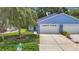 Charming blue house with a two-car garage, well-manicured lawn, and beautiful landscaping at 13321 Norman Cir, Hudson, FL 34669