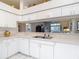 Clean kitchen with white cabinets, stainless steel sink, and a view of the living area at 13321 Norman Cir, Hudson, FL 34669