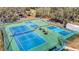 A high angle view shows multiple blue and green tennis courts with picnic tables and benches between them at 13321 Norman Cir, Hudson, FL 34669