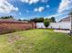 Large grassy backyard featuring a brick wall, white fence, and privacy landscaping at 14655 Potterton Cir, Hudson, FL 34667