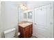 A bathroom featuring a vanity with wood cabinets and a large mirror with lighting fixture, next to a white door at 14655 Potterton Cir, Hudson, FL 34667