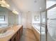 Well-lit bathroom featuring a soaking tub, glass-enclosed shower, and double vanity sinks at 14655 Potterton Cir, Hudson, FL 34667