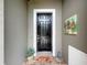 Dark wood front door with brick entry mat, adjacent to gray wall with colorful birdhouse art at 14655 Potterton Cir, Hudson, FL 34667
