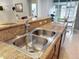 Stainless steel sink, breakfast bar area with seating, and stone countertops in the open kitchen at 14655 Potterton Cir, Hudson, FL 34667