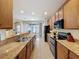 Kitchen showcasing stone countertops, stainless appliances, and wooden cabinetry with tile flooring at 14655 Potterton Cir, Hudson, FL 34667