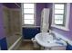 A purple bathroom with a white sink, toilet, tub, and a blue-painted wainscoting accent at 1601 Dixie Hwy, Tarpon Springs, FL 34689