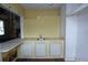 A yellow kitchen area with a sink, base cabinets, and an open layout into another room at 1601 Dixie Hwy, Tarpon Springs, FL 34689