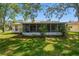View of the home's back exterior featuring a screened-in lanai and lush lawn at 2183 Westchester Blvd, Spring Hill, FL 34606