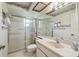 Bathroom with shower cabin, white toilet, sink and big mirror with flower-themed wallpaper above at 2183 Westchester Blvd, Spring Hill, FL 34606