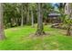 The backyard offers a large grassy area with mature trees and a view of a screen enclosed pool at 2202 Amity Ct, New Port Richey, FL 34655
