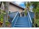 Back of the house with blue stairs leading to a deck; greenery and trees surround the property at 2202 Amity Ct, New Port Richey, FL 34655