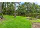 Large green lawn with mature trees leading to a pond; a fire pit is in the corner of the yard at 2202 Amity Ct, New Port Richey, FL 34655