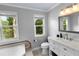 Bright bathroom with a white vanity, toilet, and tub under windows providing views of a pond and landscaping at 2202 Amity Ct, New Port Richey, FL 34655