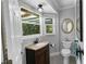 A quaint bathroom featuring light gray walls, tiled floors, a vanity, and a window with natural light at 2202 Amity Ct, New Port Richey, FL 34655