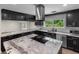 Beautiful kitchen showcasing an island cooktop, black cabinets, granite countertops, stainless steel appliances and natural light at 2202 Amity Ct, New Port Richey, FL 34655