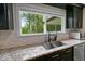 A close-up shot of the Kitchen sink featuring granite countertops, dark cabinets, stainless steel appliances, and a view of the outdoors at 2202 Amity Ct, New Port Richey, FL 34655