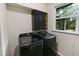 Contemporary laundry room with black washer/dryer, sleek cabinets and a bright window at 2202 Amity Ct, New Port Richey, FL 34655