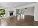 Bright living area featuring wood floors, fireplace, and large windows showcasing outdoor greenery at 2202 Amity Ct, New Port Richey, FL 34655
