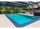 Enclosed pool area featuring a turquoise swimming pool, bar, hot tub, and views of lush greenery at 2202 Amity Ct, New Port Richey, FL 34655