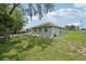 A view of the spacious, grassy backyard featuring the back of the house and a fire pit at 2251 Evenglow Ave, Spring Hill, FL 34609